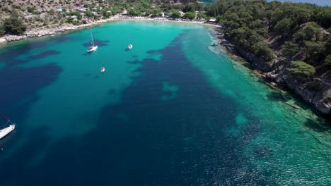 slow, cinematic aerial reveal of aliki beach with turquoise water and mountains covered by lush vegetation in the background, thassos, greece