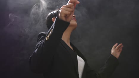side view of asian conductor woman holding a baton and showing gesture quickly in the black studio with fog