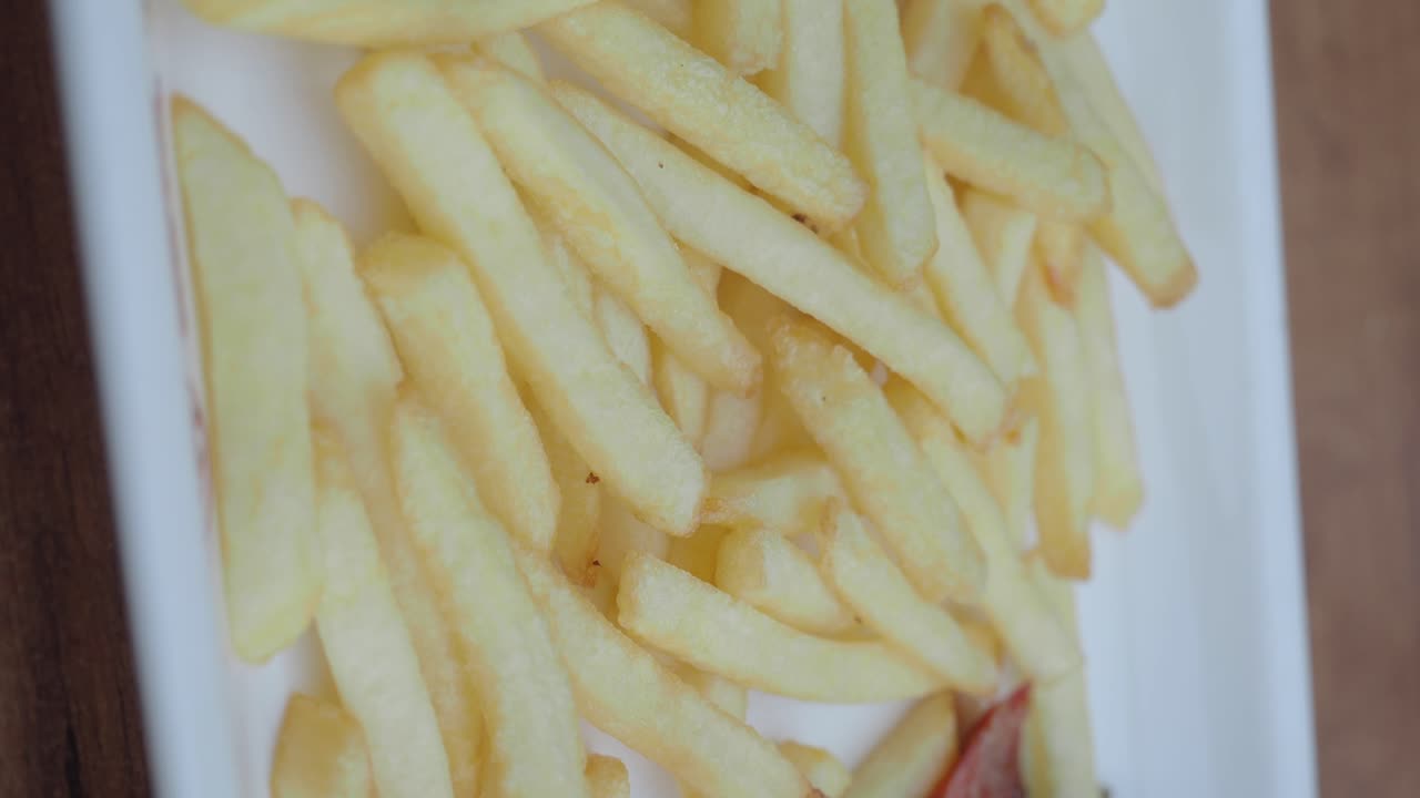 Close-up of a plate with meat and vegetable stir-fry, french fries, and sauce