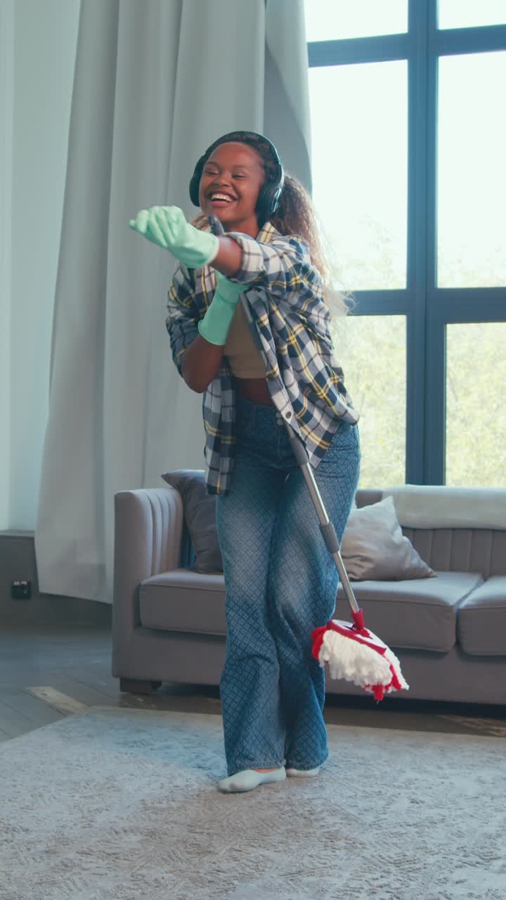 Young woman enjoys cleaning while listening to music at home