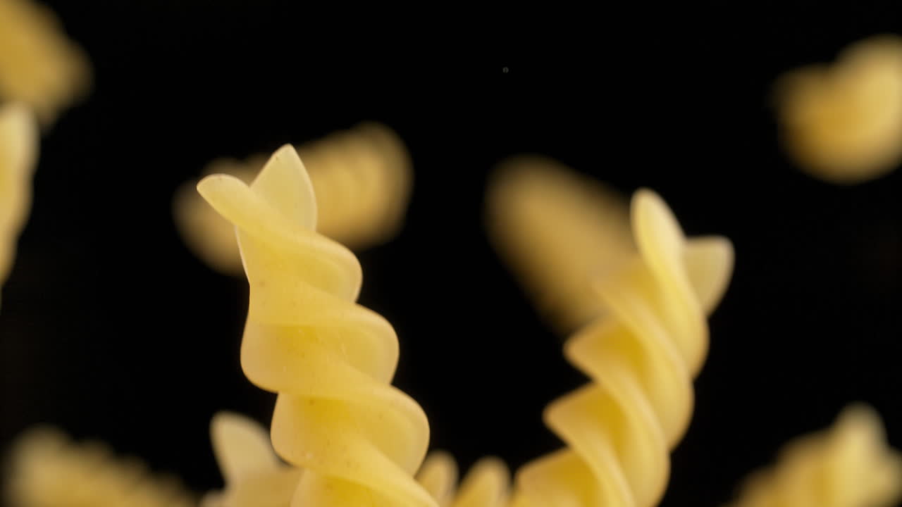 Uncooked Fusilli Pasta Flying On The Black Background In Slow Motion And Macro