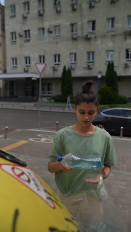 woman recycling plastic bottle in city street