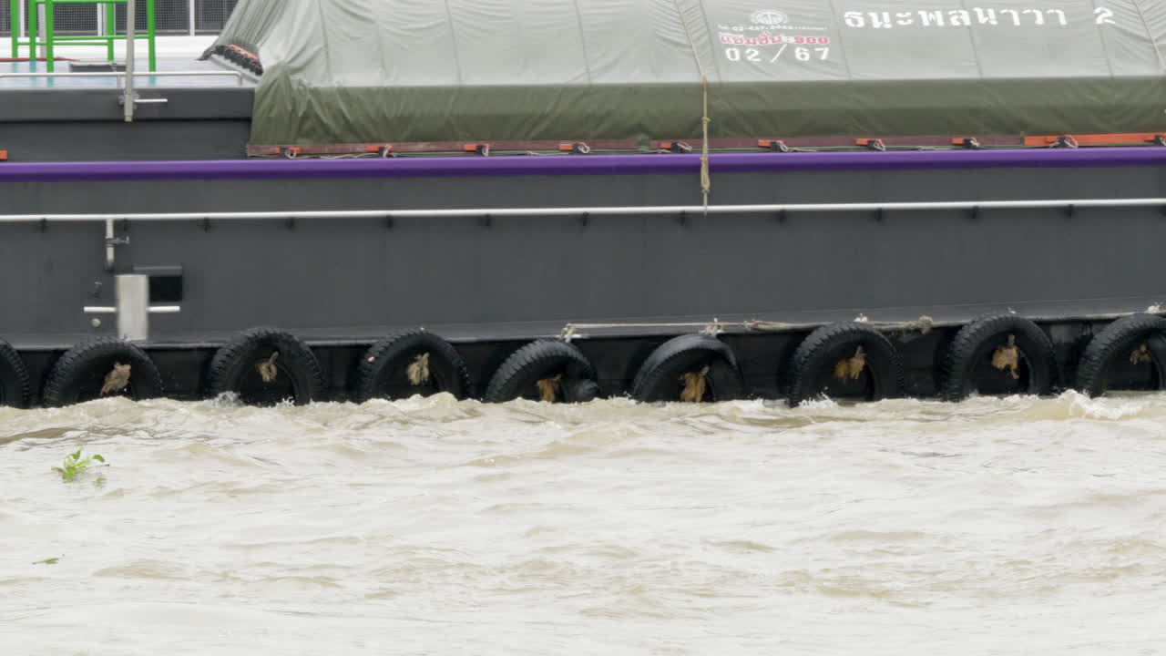 Cargo barges moving along the flooded Chao Phraya River, a major waterway in the city of Bangkok in Thailand.
