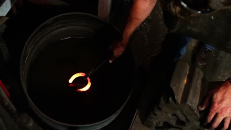 blacksmith cooling a horseshoe in water