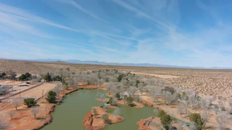 volando rápido en un dron fpv sobre un parque con un estanque en el desierto de mojave