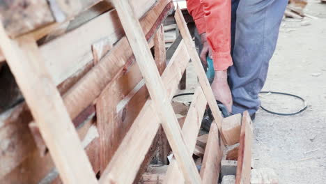 man using electric saw to cut wooden pallets