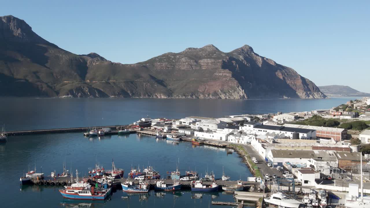 잔잔한 물에 많은 보트가 있고 배경에 채프먼의 봉우리가 있는 남아프리카 하우트 베이 항구