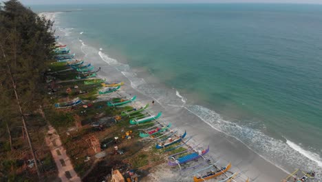 Wide-shot-of-Serdang-beach-with-fishing-boats-on-shore-at-Belitung,-aerial