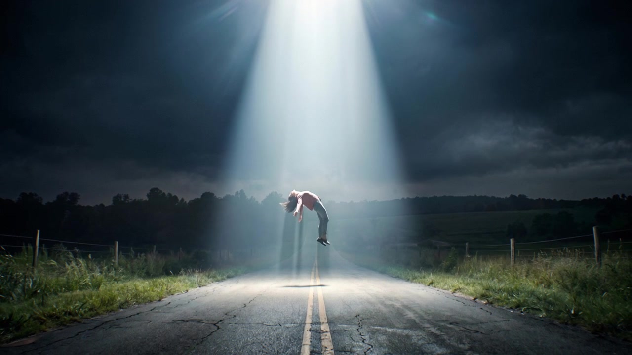 Person Being Abducted by Alien Spaceship on Rural Road at Night