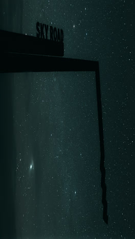 beautiful timelapse of stars rotating backdropping the sky road sign in connemara, cosmic wanderlust in motion. vertical video
