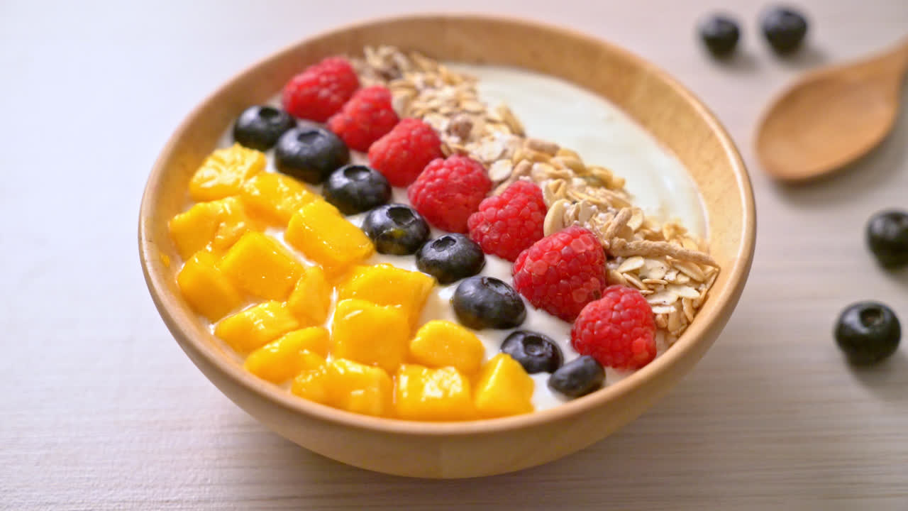 tazón de yogur casero con frambuesa, arándano, mango y granola - estilo de comida saludable