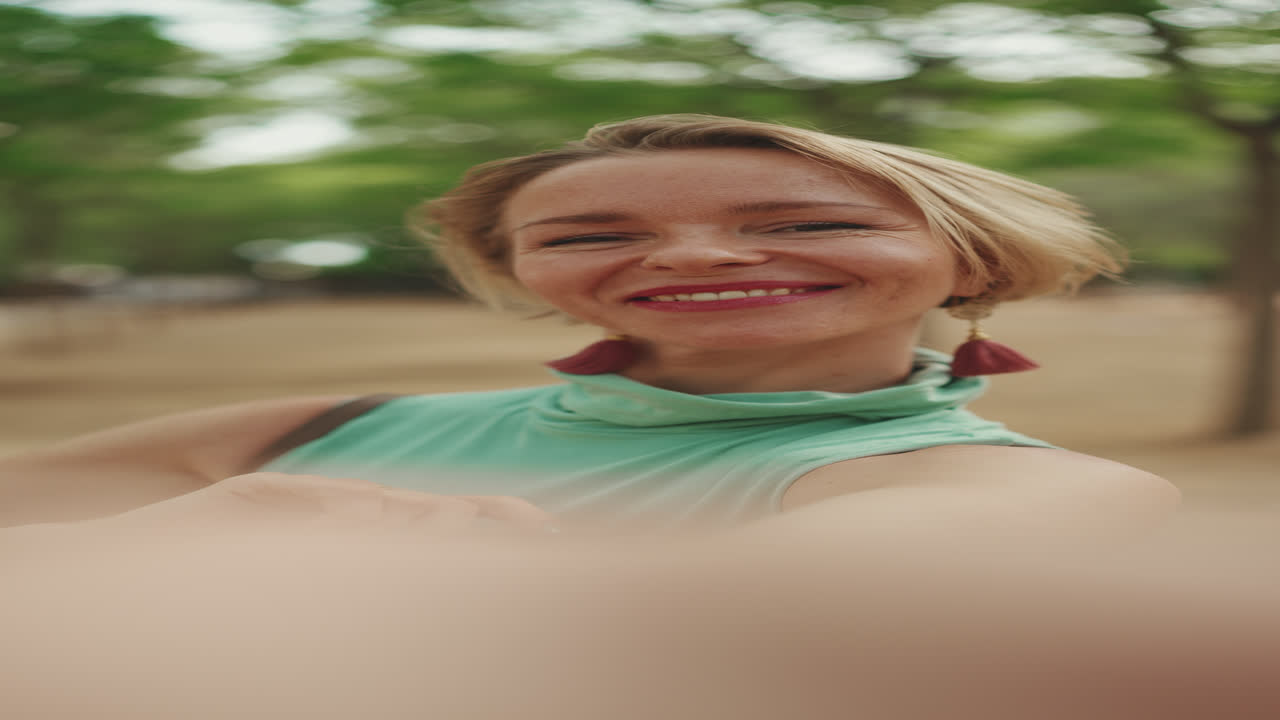 Hymyilevä nainen ottaa selfien ulkona
