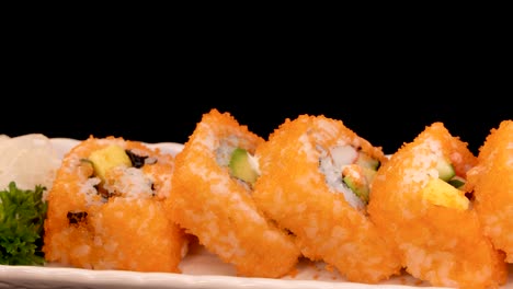 california roll sushi pieces rotate smoothly on a white plate against a black background, with even studio lighting and a seamless camera pan