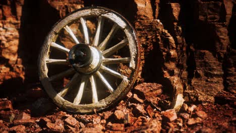 old wooden cart wheel on stone rocks