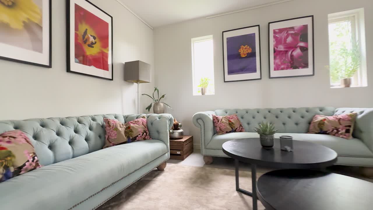 Interior de sala de estar moderna e iluminada com sofás azul-claros e elegante arte floral na parede