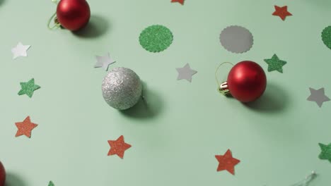 christmas decorations with silver and red bauble on green background