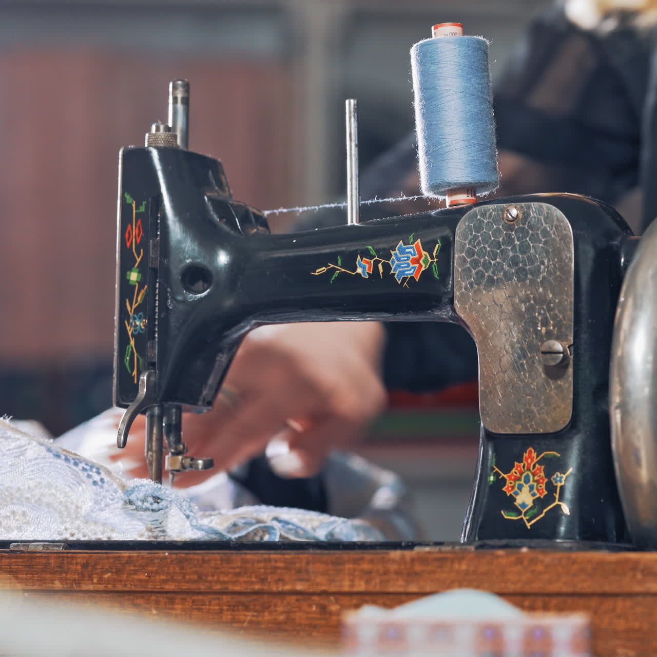 Female tailor works on a sewing machine at her workplace. Successful tailor sewing clothes in atelier with black sewing machine.