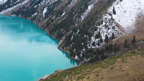 cinematic drone footage of the turquoise colored lake water at big almaty lake in the trans-ili alatau mountains in kazakhstan