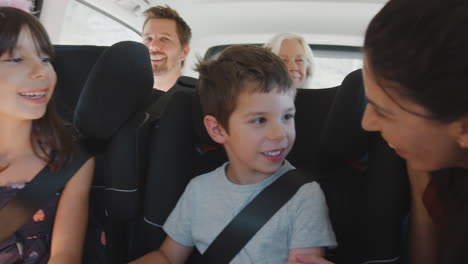 multi generation family sitting in back of people carrier being driven to vacation