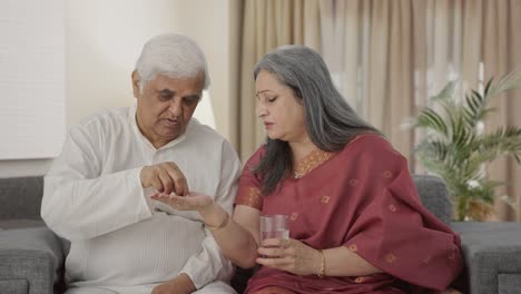 fürsorgliche alte indische frau, die ihrem kranken mann medizin gibt