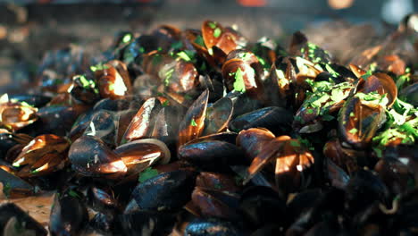 Closeup-mussels-with-herbs-cooking-on-frying-pan.-Clams-grilling-on-open-air