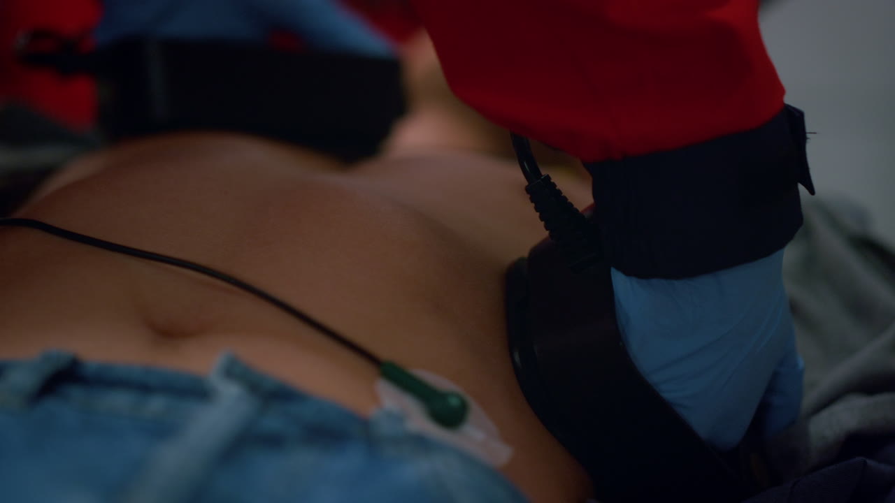 Unrecognizable EMS paramedic hands making cpr with defibrillator on patient body