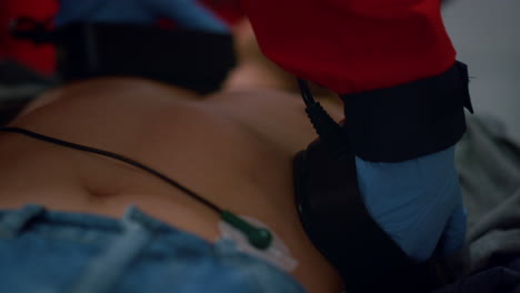 unrecognizable ems paramedic hands making cpr with defibrillator on patient body