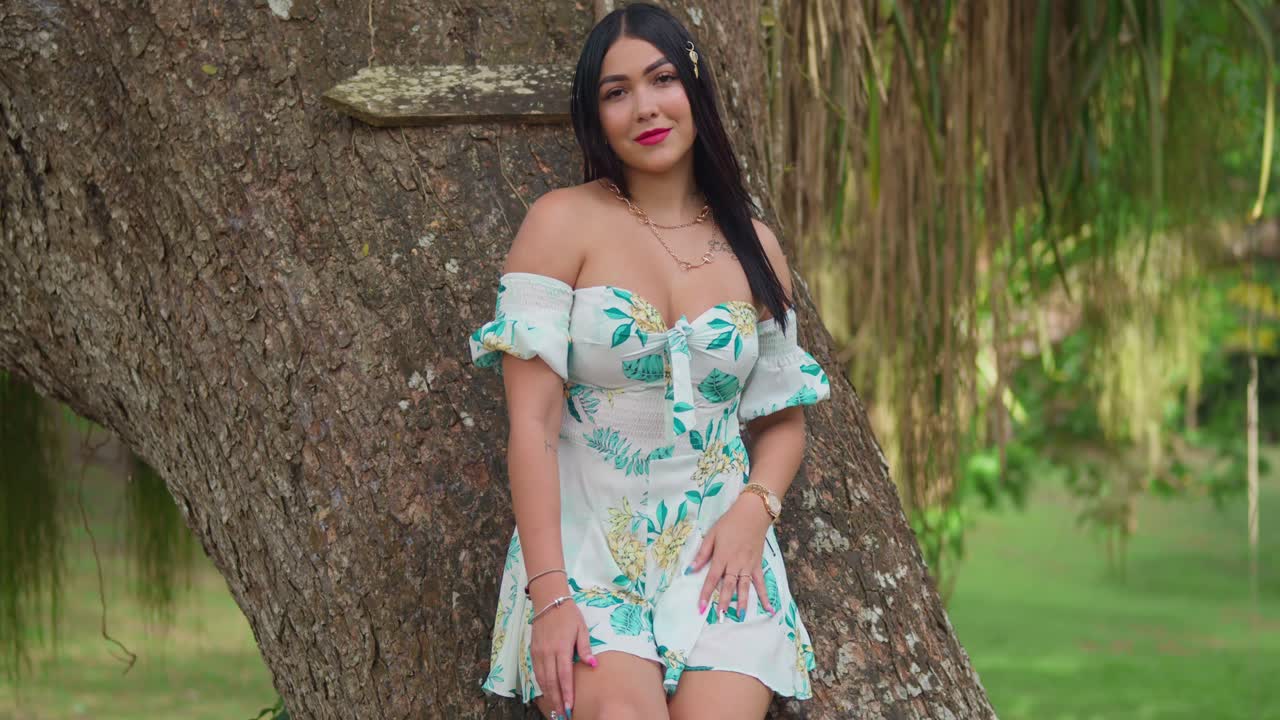 히스패닉 여성 은 공원 에서  ⁇ 은 날 에 큰 나무 줄기 에 기대어 있다