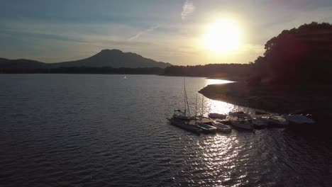 Vista-Aérea-De-Una-Puesta-De-Sol-Sobre-Un-Muelle-Con-Barcos-En-Un-Lago-Del-Sur-De-España