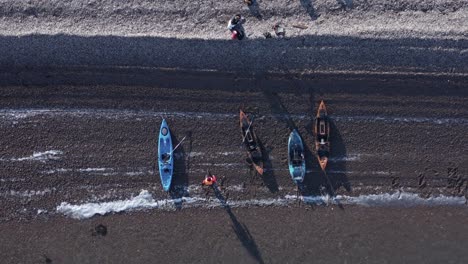 Top-down-of-kayak-group-resting-on-pebble-beach-in-Iceland,-aerial