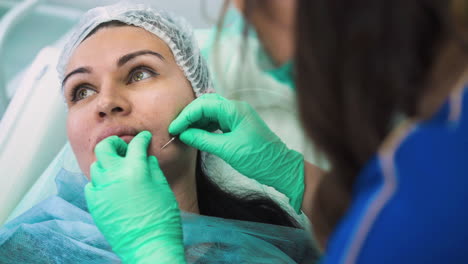 mujer hace inyección de relleno facial con jeringa al cliente
