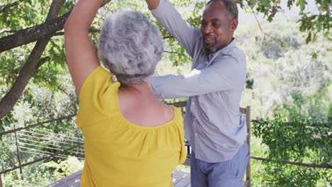 Älterer-Afroamerikanischer-Ehemann-Und-Gemischtrassige-Ehefrau-Tanzen-Und-Lachen-Gemeinsam-Im-Garten