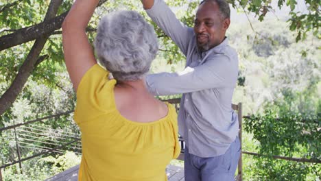 el marido afroamericano mayor y la esposa de raza mixta bailando y riendo juntos en el jardín