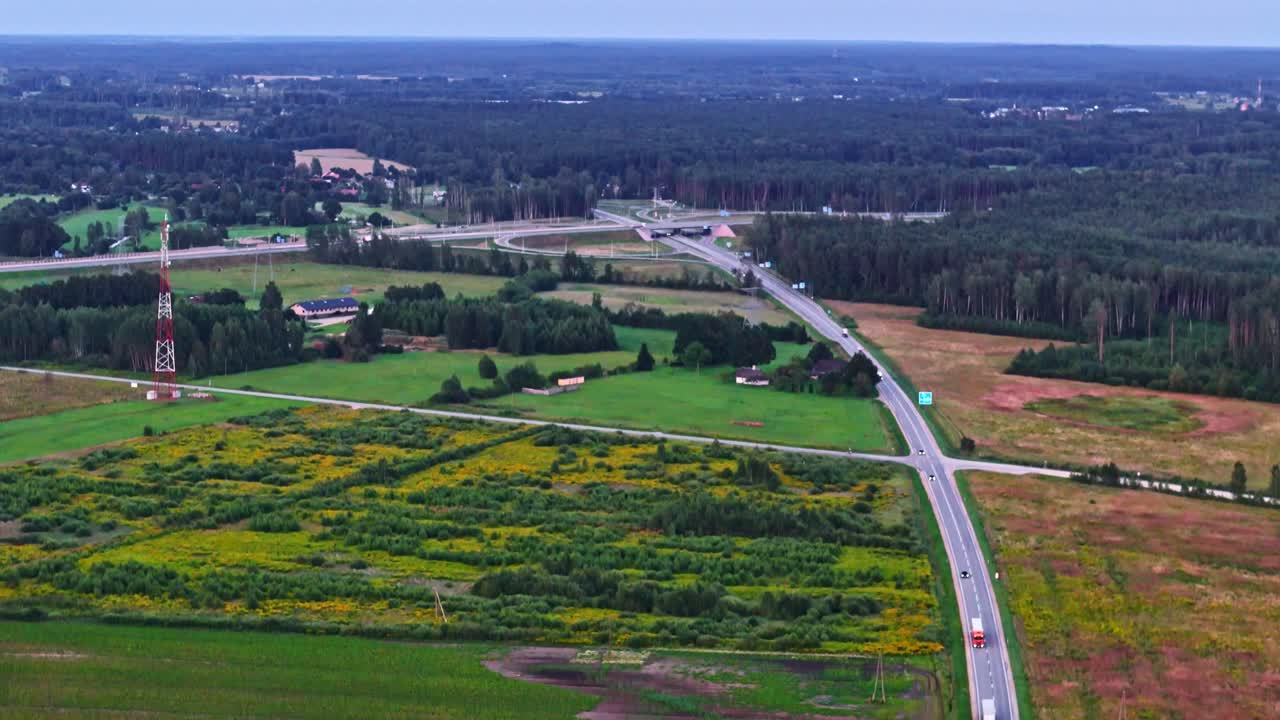 Aerial view of highway interchange in countryside near forest and rural housing