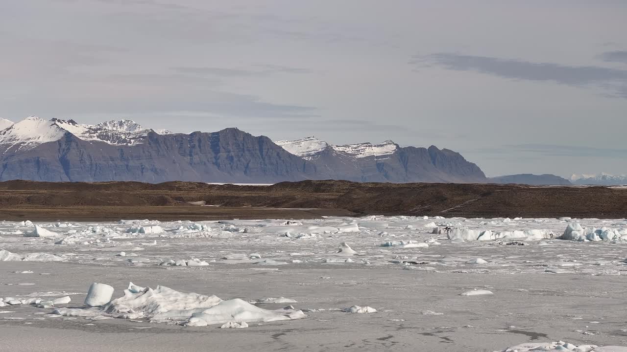 Iceland’s Fjallsárlón Glacier Lagoon - aerial view with snowy landscape, floating icebergs and Vatnajökull mountains.