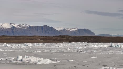 iceland’s fjallsárlón glacier lagoon - aerial view with snowy landscape, floating icebergs and vatnajökull mountains.