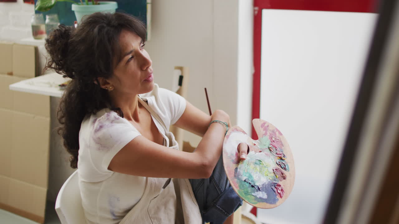 두 인종의 여성이 빛나는 스튜디오에서 그림을 그리고, 복사 공간이 있습니다.