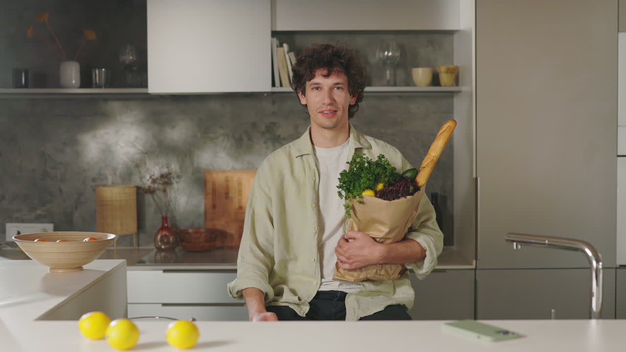 A Young Man Holding a Bag of Groceries in a Modern Kitchen