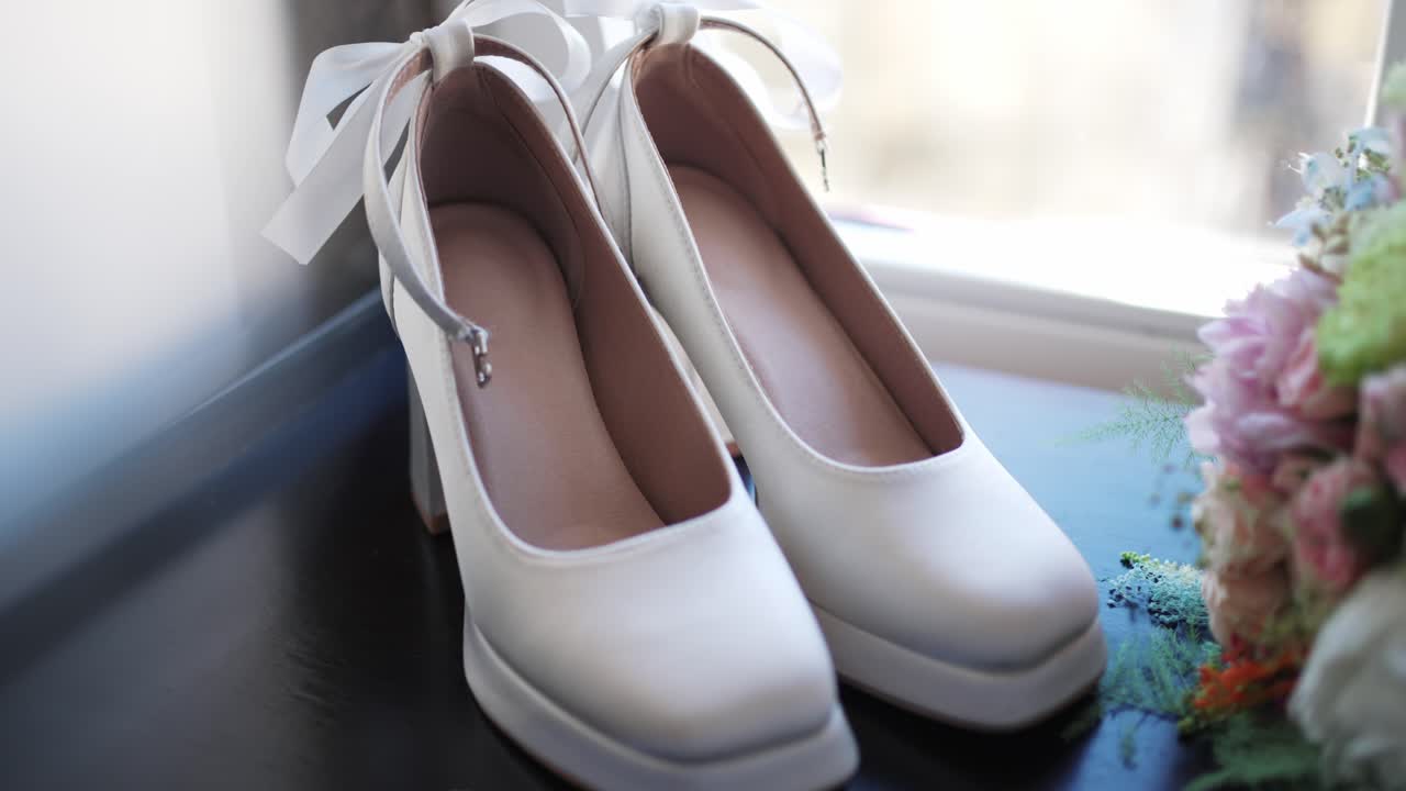 창가 빛 근처에 놓인 흰색 웨딩 슈즈 한 켤레