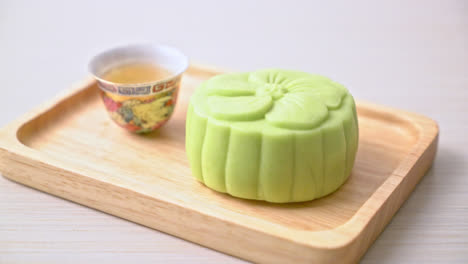 Chinese-moon-cake-green-tea-flavour-with-tea-on-wood-plate