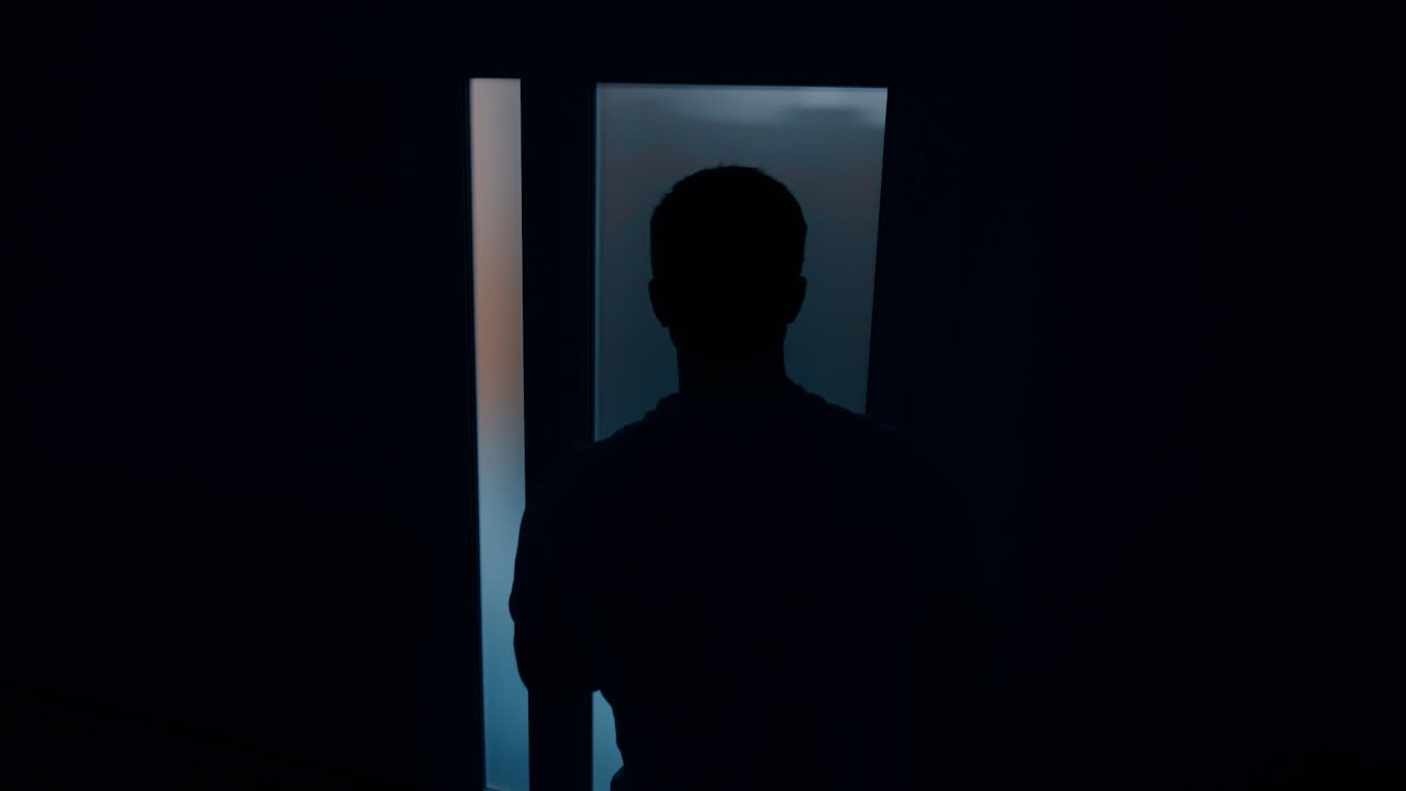 Male silhouette near the door to a delivery room. Worried husband waiting for his wife giving birth to a child.