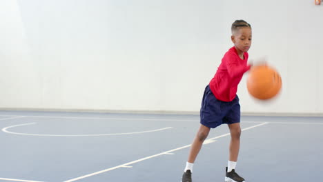practicing dribbling on indoor court, boy focused and active, copy space