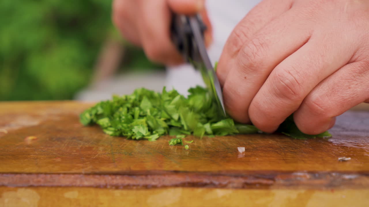 Chef cuts fresh organic parsley on wooden board, close view