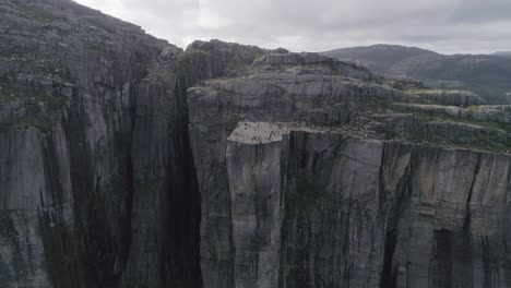 aerial slomo shot flying towards preikestolen with tourists walking and photographing the scenery