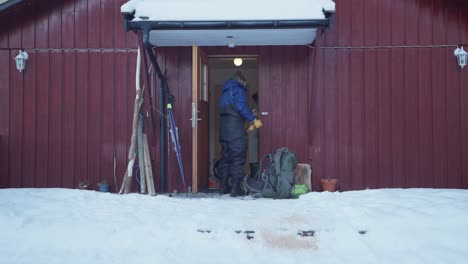 man open the woodes door of cabin then put a leash on alaskan malamute