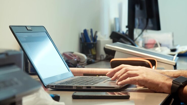 Mandehænder taster på et tastatur til en bærbar computer.