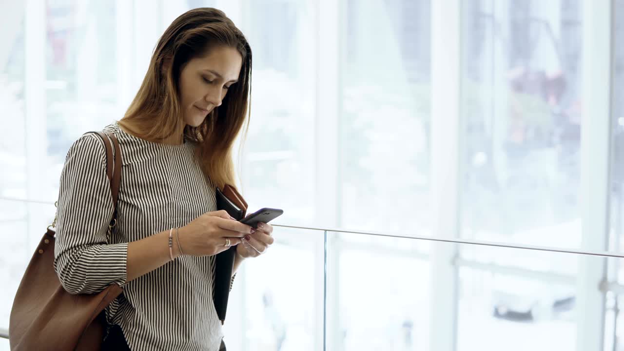 joven mujer de negocios hermosa usando el teléfono inteligente en el edificio de oficinas. mujer ocupada bajando por la escalera mecánica