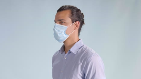 man in button up shirt puts on face mask, angled profile closeup facing left