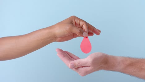 Hands-of-diverse-people-giving-blood-drop-on-blue-background,-slow-motion