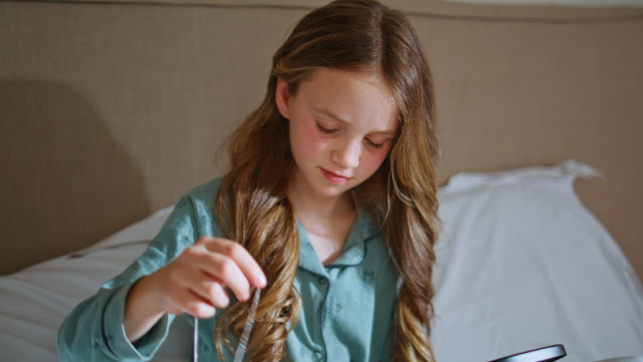 Pyjamas kid playing jewellery looking in mirror closeup. Girl choosing necklaces